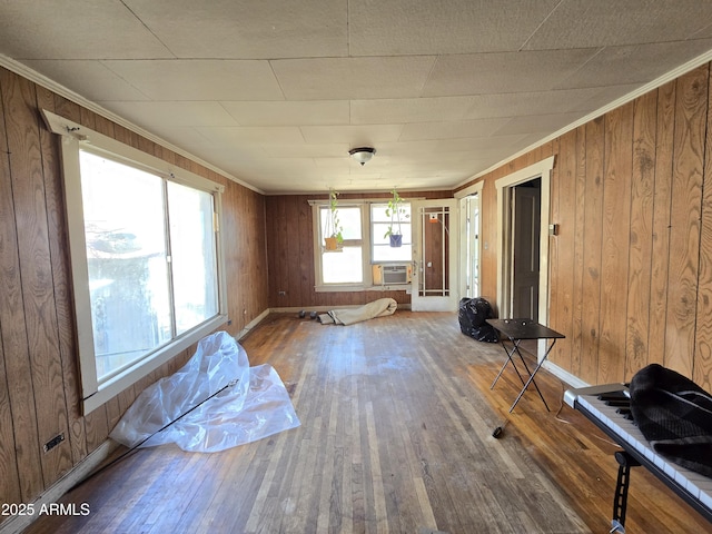 empty room featuring hardwood / wood-style floors, wooden walls, and crown molding