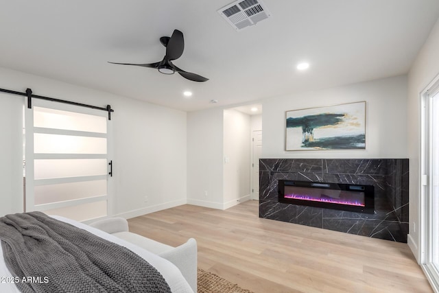 1736 N Ashbrook Cir, Mesa, AZ 85213 - bedroom featuring light wood-type flooring, a barn door, recessed lighting, a high end fireplace, and ceiling fan