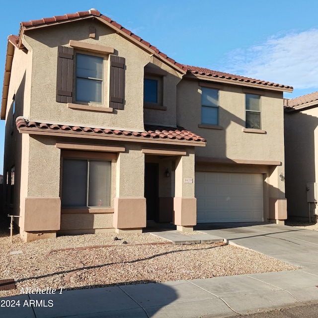 mediterranean / spanish home featuring a garage, driveway, a tile roof, and stucco siding