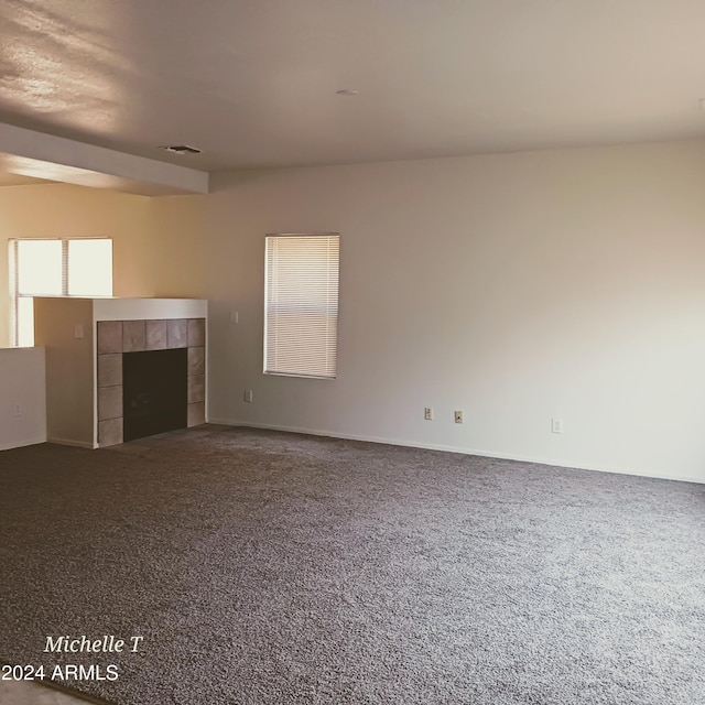 unfurnished living room with a tiled fireplace and carpet