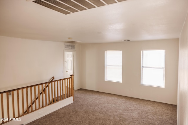 carpeted spare room with visible vents and baseboards