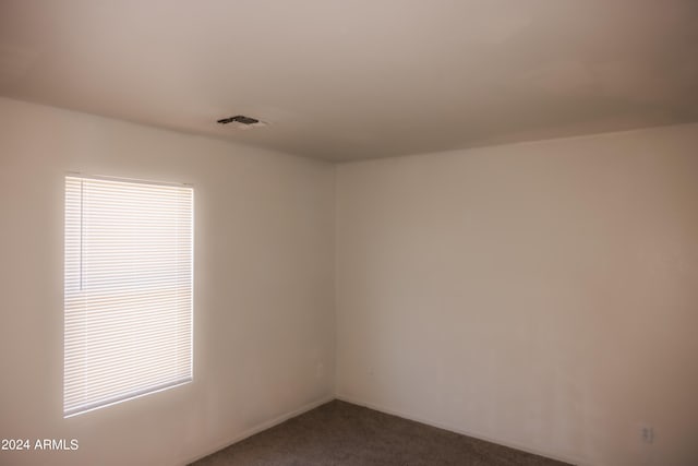 spare room featuring visible vents and dark carpet