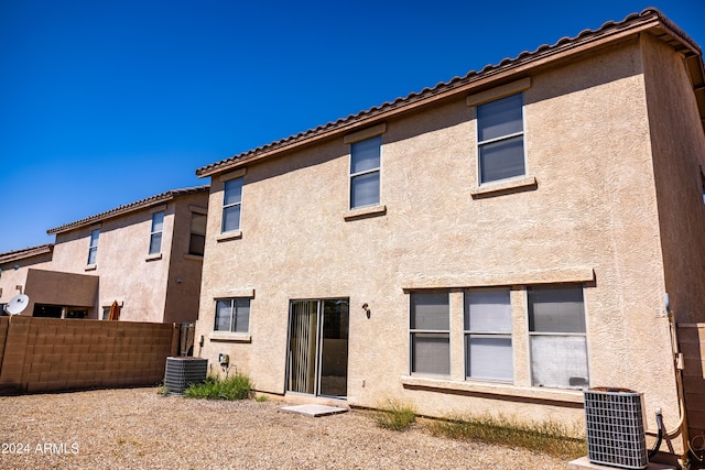 back of house featuring a tile roof, fence, cooling unit, and stucco siding