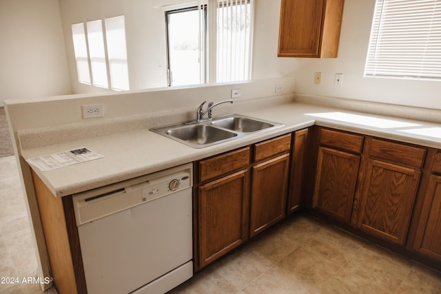 kitchen with brown cabinetry, light countertops, dishwasher, and a sink