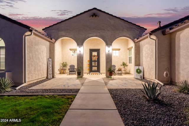 exterior entry at dusk with a patio area