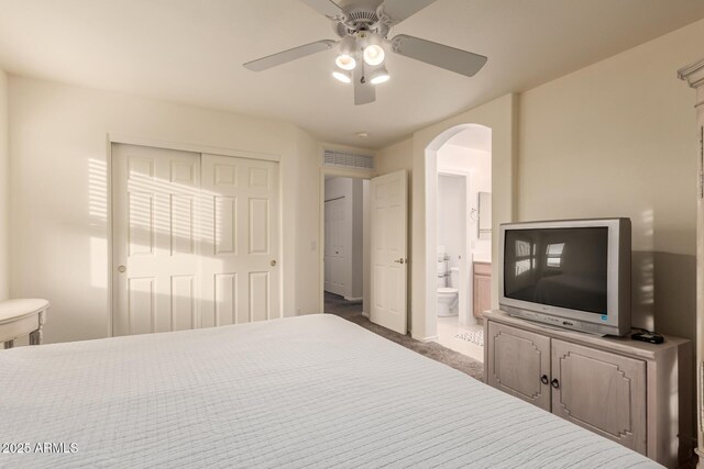 bedroom featuring arched walkways, ceiling fan, visible vents, a closet, and dark carpet