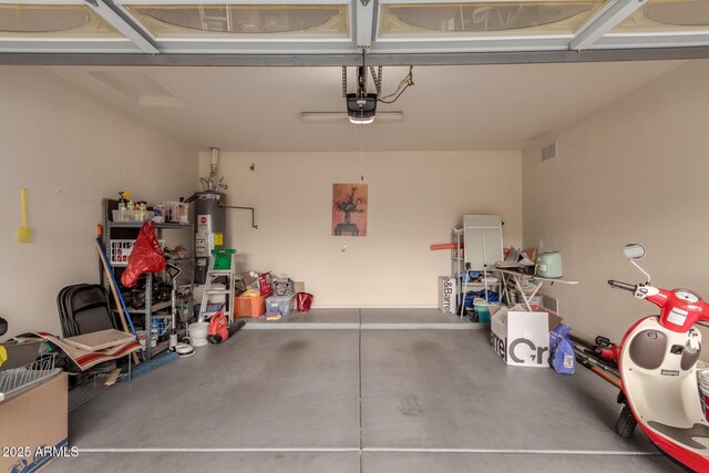 garage featuring gas water heater, visible vents, and a garage door opener