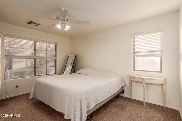 carpeted bedroom featuring ceiling fan, multiple windows, visible vents, and baseboards