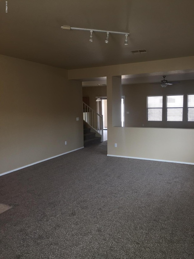 carpeted spare room featuring track lighting and ceiling fan