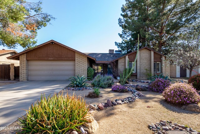 mid-century modern home with brick siding, an attached garage, and concrete driveway