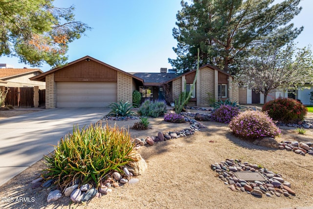 mid-century modern home featuring brick siding, concrete driveway, an attached garage, and fence