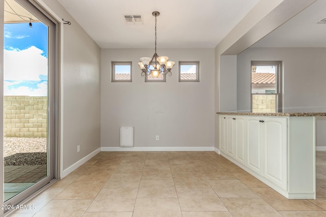 unfurnished dining area featuring light tile patterned flooring and a chandelier