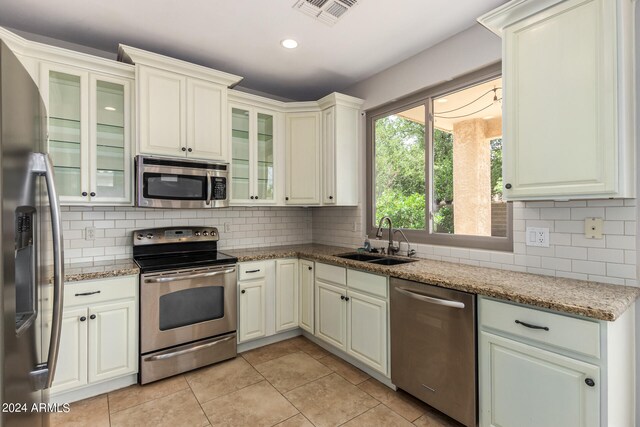 kitchen featuring light stone countertops, stainless steel appliances, backsplash, and sink