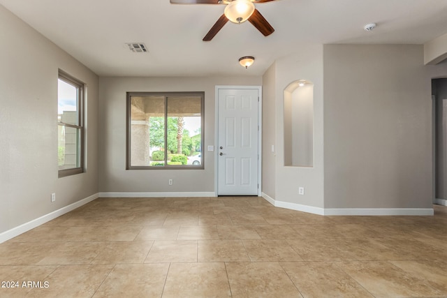 tiled empty room featuring a wealth of natural light and ceiling fan