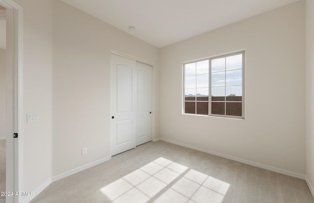 unfurnished bedroom with light carpet and a closet