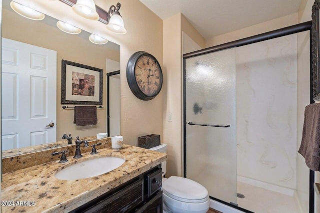 bathroom with a shower with door, vanity, and toilet