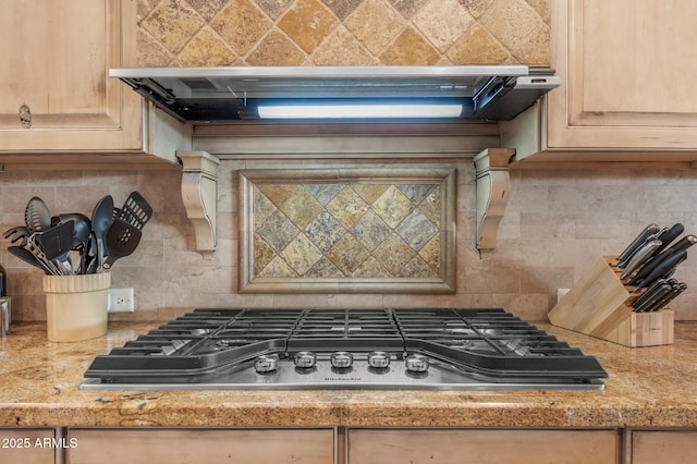 interior details featuring backsplash, light stone counters, stainless steel gas cooktop, exhaust hood, and light brown cabinets