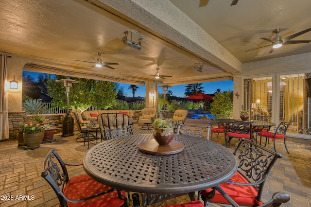 patio terrace at dusk with ceiling fan and an outdoor living space