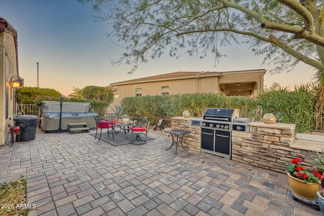 patio terrace at dusk with area for grilling, a grill, and a hot tub