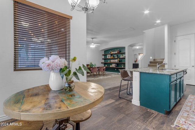 kitchen with sink, built in features, dark hardwood / wood-style floors, an island with sink, and blue cabinets