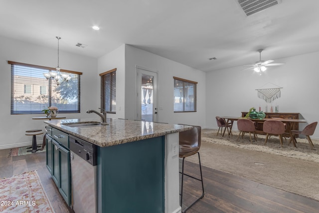 kitchen with sink, a breakfast bar area, hanging light fixtures, dishwasher, and an island with sink