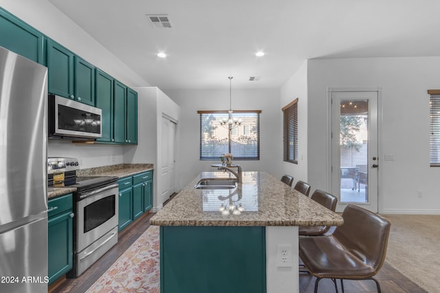 kitchen with sink, appliances with stainless steel finishes, a center island with sink, a kitchen bar, and decorative light fixtures