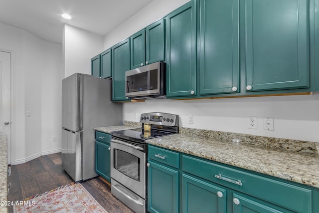 kitchen featuring dark wood-type flooring, light stone countertops, green cabinetry, and appliances with stainless steel finishes