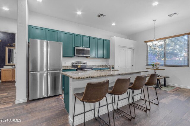 kitchen featuring stainless steel appliances, light stone countertops, a kitchen island with sink, and a kitchen bar