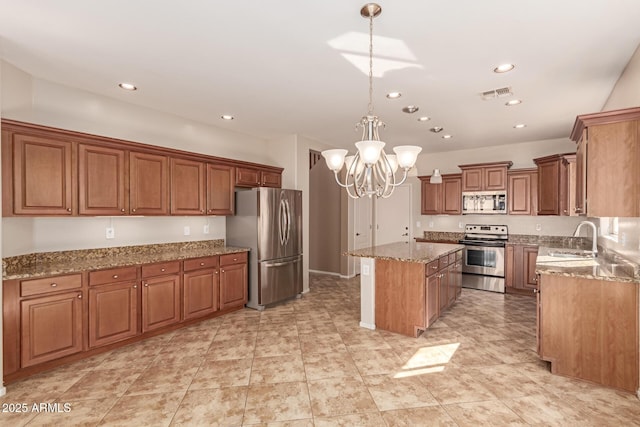 kitchen with stainless steel appliances, light stone countertops, a kitchen island, and decorative light fixtures