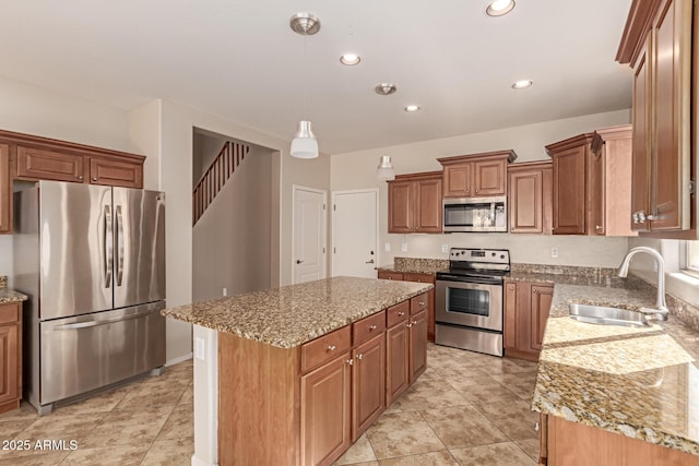 kitchen featuring sink, light stone counters, decorative light fixtures, appliances with stainless steel finishes, and a kitchen island