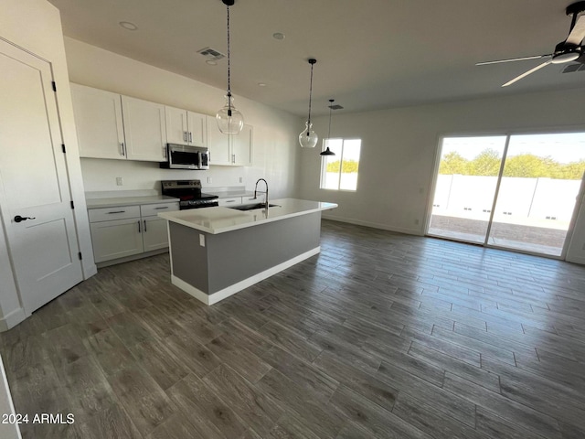 kitchen with stainless steel appliances, decorative light fixtures, white cabinets, dark hardwood / wood-style floors, and an island with sink