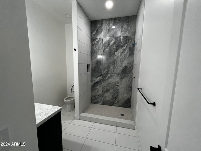 bathroom with tile patterned flooring, a tile shower, vanity, and toilet