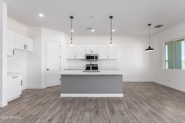 kitchen with white cabinetry, hanging light fixtures, stainless steel appliances, an island with sink, and light wood-type flooring