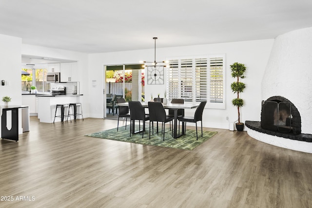 dining room featuring a fireplace, baseboards, and light wood-style flooring