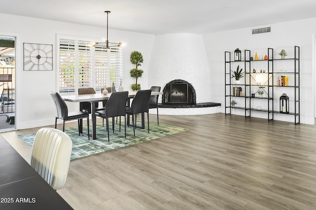 dining area with an inviting chandelier, wood finished floors, visible vents, and a fireplace