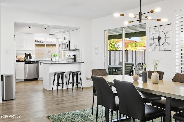 dining area with plenty of natural light, light wood-type flooring, and an inviting chandelier
