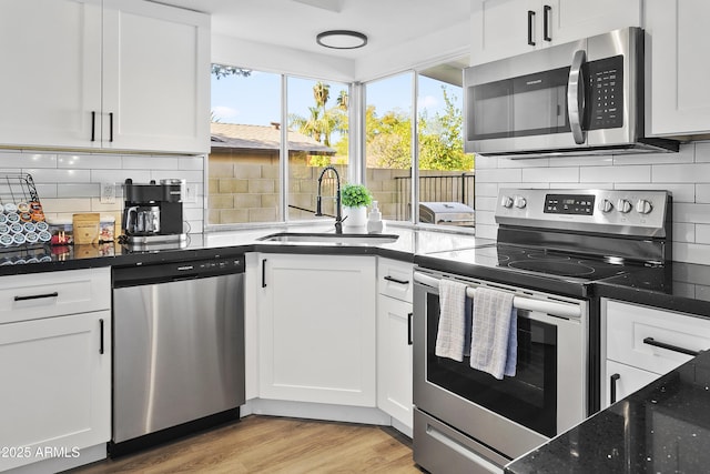 kitchen featuring backsplash, appliances with stainless steel finishes, white cabinetry, and a sink