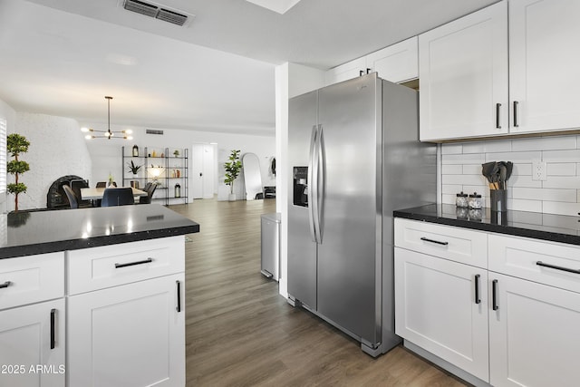 kitchen featuring dark wood finished floors, dark countertops, visible vents, tasteful backsplash, and stainless steel refrigerator with ice dispenser
