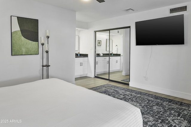 bedroom featuring connected bathroom, visible vents, and light wood-style flooring
