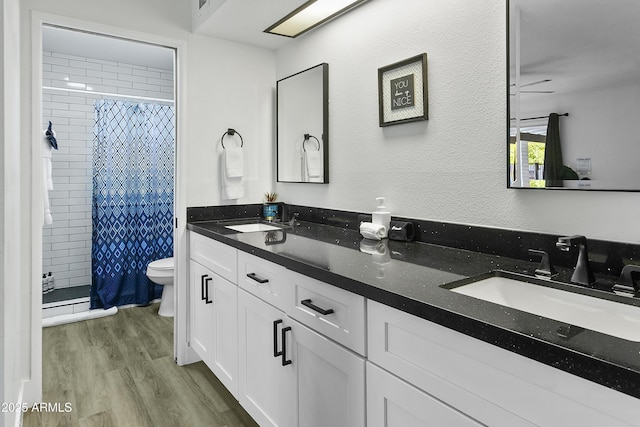 bathroom featuring a stall shower, wood finished floors, a sink, and toilet