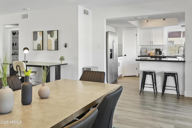 dining area with light wood-type flooring and visible vents