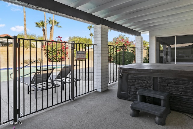 view of patio featuring a hot tub, an outdoor pool, and fence