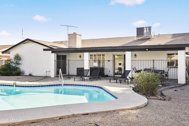 pool featuring a patio area, central AC unit, and fence
