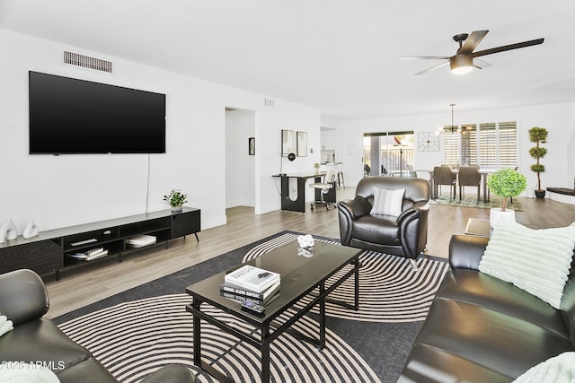 living area featuring visible vents, baseboards, wood finished floors, and ceiling fan