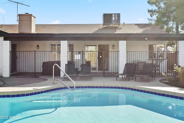 exterior space with central air condition unit, a community pool, a patio area, and a shingled roof
