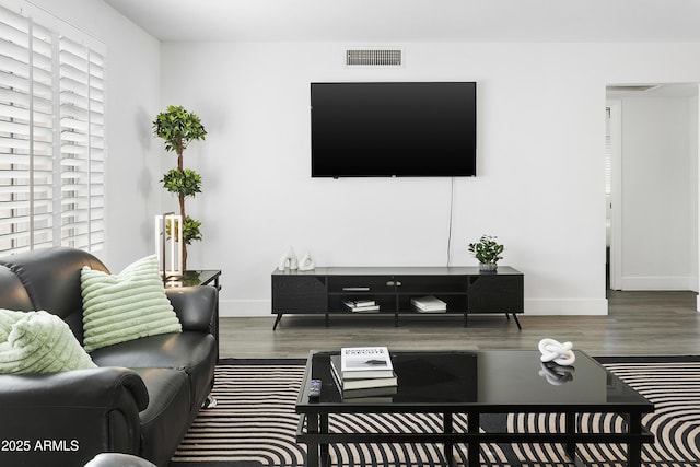 living area featuring baseboards, wood finished floors, and visible vents