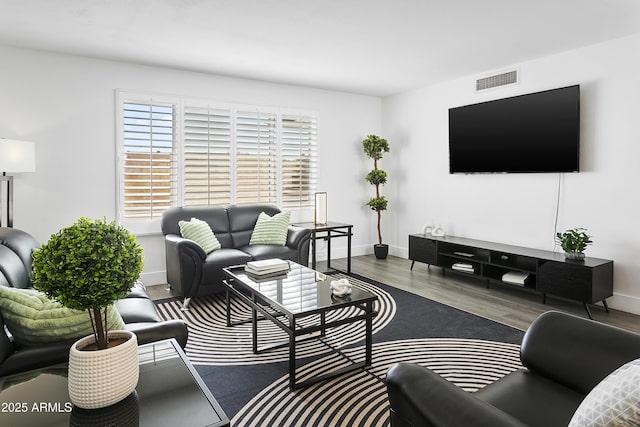 living area with wood finished floors, visible vents, and baseboards
