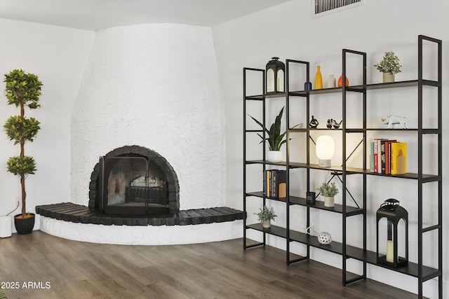 unfurnished living room featuring a fireplace with raised hearth, wood finished floors, and visible vents