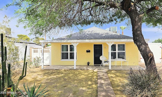 view of front of house with concrete block siding, roof with shingles, and fence