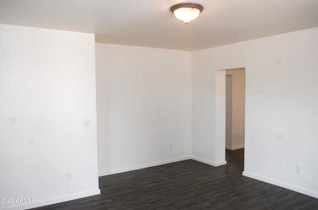empty room with dark wood-style floors and baseboards
